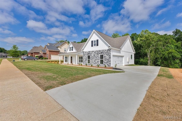 view of front of house featuring an attached garage, stone siding, board and batten siding, a front yard, and driveway