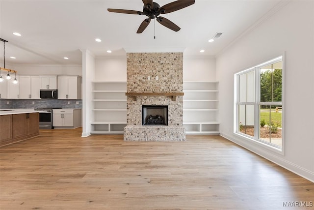 unfurnished living room with ceiling fan, visible vents, ornamental molding, and light wood finished floors