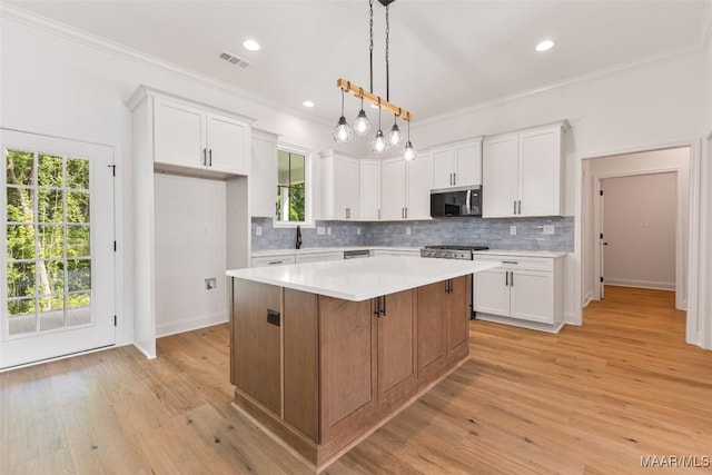 kitchen featuring a kitchen island, stainless steel appliances, visible vents, and white cabinetry