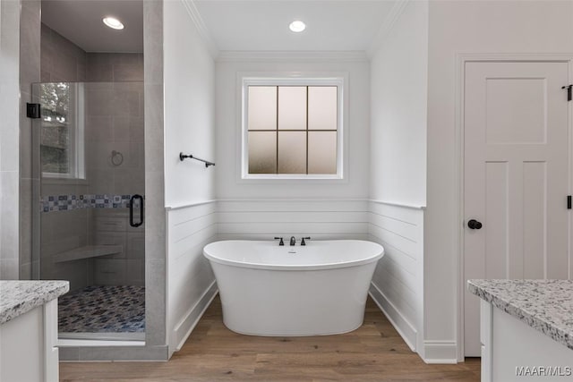 bathroom featuring vanity, a shower stall, wood finished floors, ornamental molding, and a soaking tub