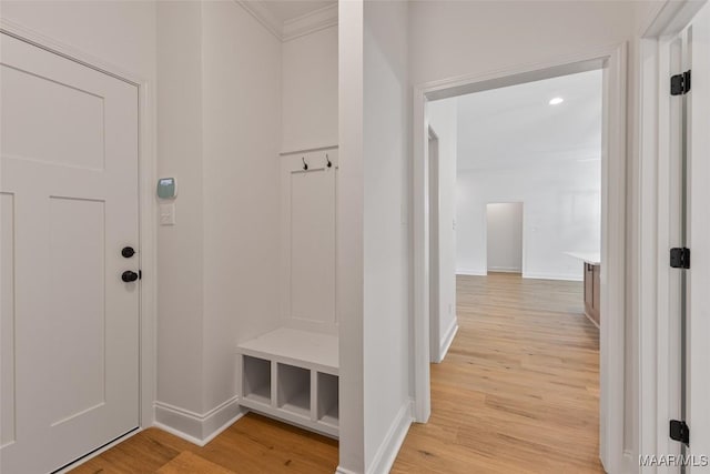 mudroom with light wood-style floors, baseboards, and crown molding