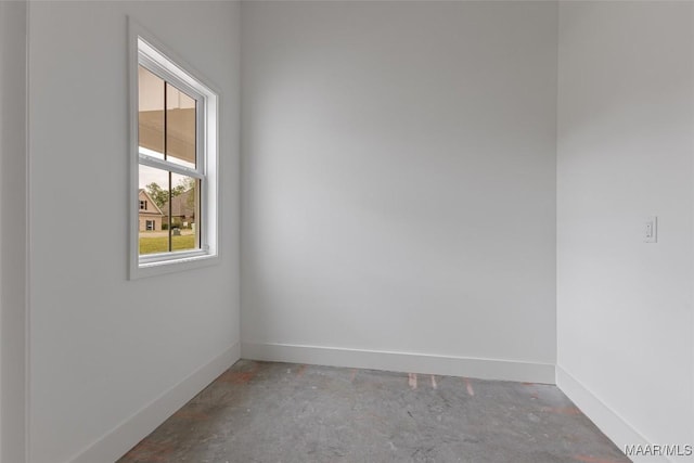 empty room featuring unfinished concrete floors and baseboards