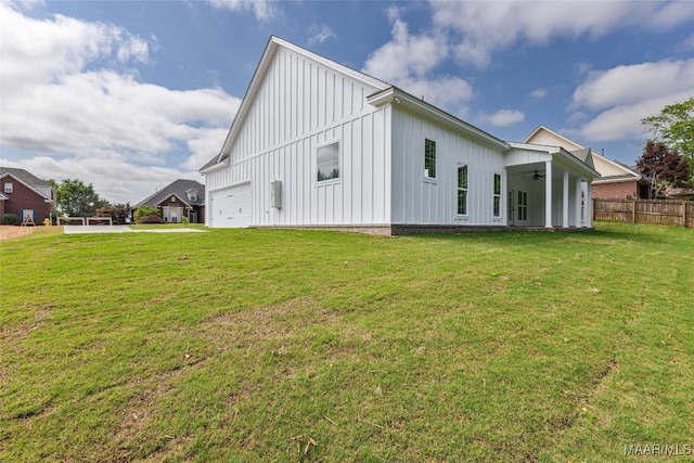 exterior space with board and batten siding, a yard, fence, and a ceiling fan