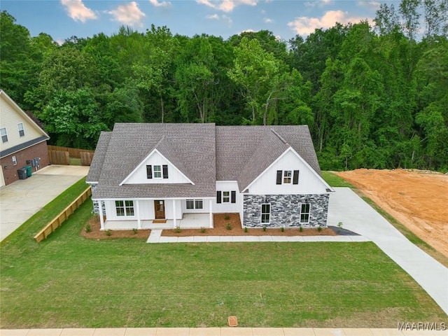 view of front of property with fence, concrete driveway, roof with shingles, and a front yard