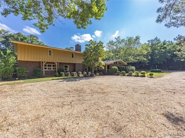 rear view of property with a chimney and brick siding