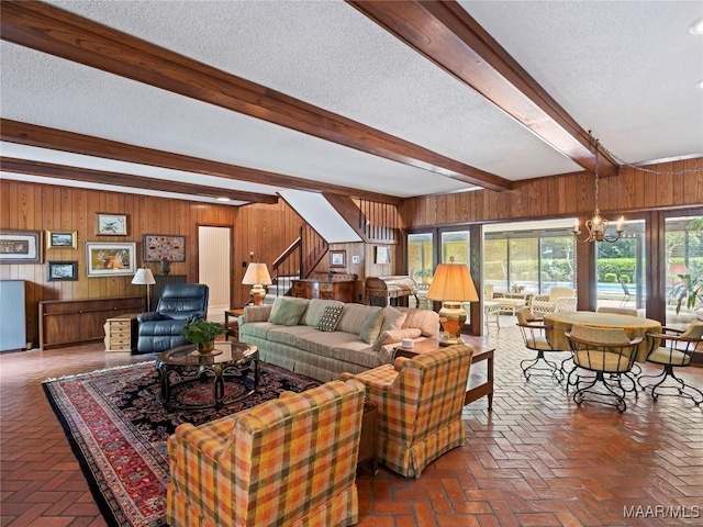 living room with wood walls, a textured ceiling, brick floor, and beamed ceiling