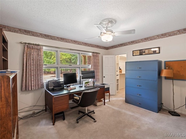office space with light colored carpet, a ceiling fan, and a textured ceiling