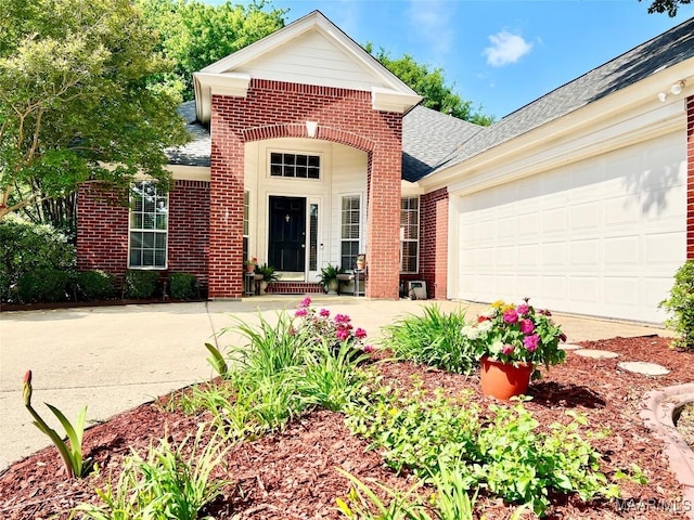 view of front of property with brick siding, a garage, roof with shingles, and driveway