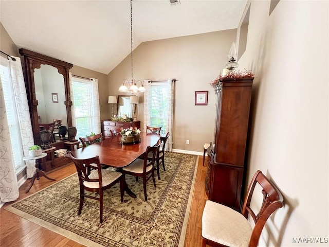dining area featuring a chandelier, wood finished floors, and vaulted ceiling