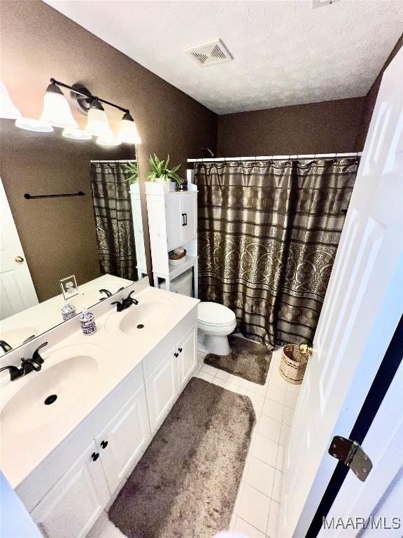 full bathroom with double vanity, tile patterned floors, visible vents, and a sink
