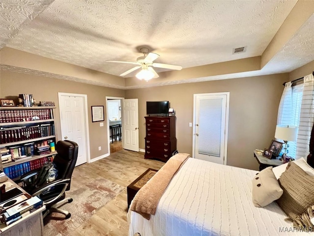 bedroom with baseboards, a textured ceiling, light wood-style flooring, and ceiling fan