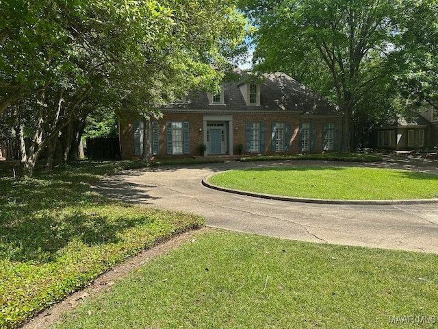 view of front of house with curved driveway, a front lawn, and brick siding