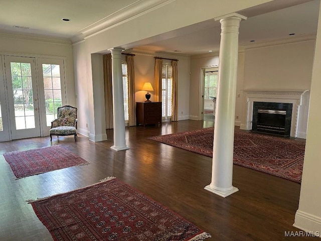 living area featuring ornate columns, crown molding, and wood finished floors