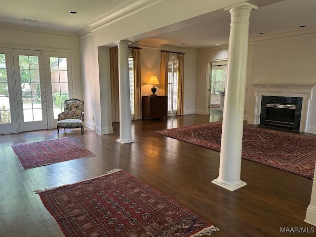 living area with crown molding, plenty of natural light, decorative columns, and a fireplace with flush hearth