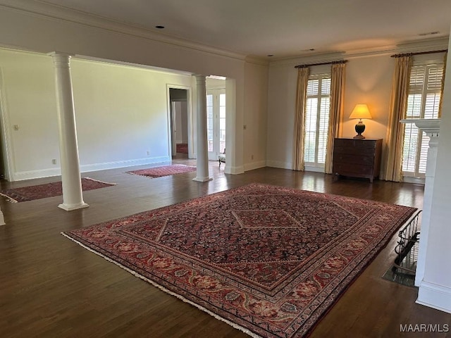 interior space featuring crown molding, ornate columns, baseboards, and wood finished floors