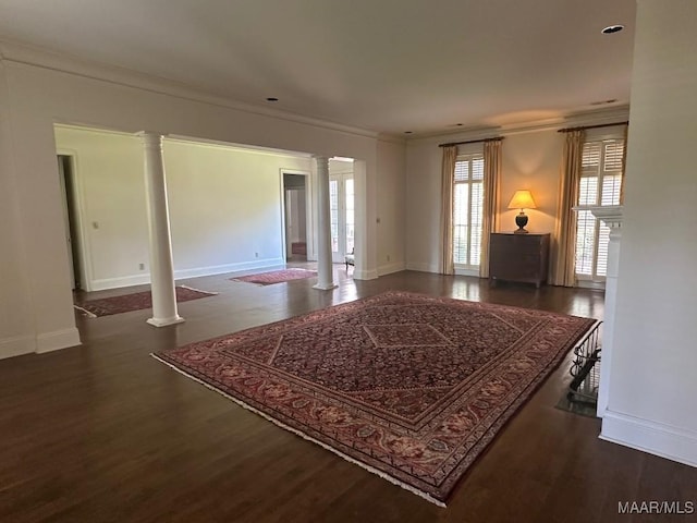 interior space with crown molding, baseboards, decorative columns, and wood finished floors