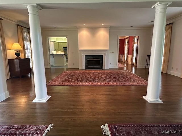 living room featuring decorative columns, crown molding, a fireplace, wood finished floors, and baseboards