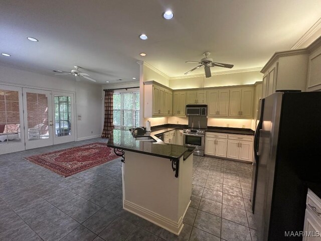 kitchen featuring dark countertops, stainless steel appliances, a ceiling fan, and a peninsula
