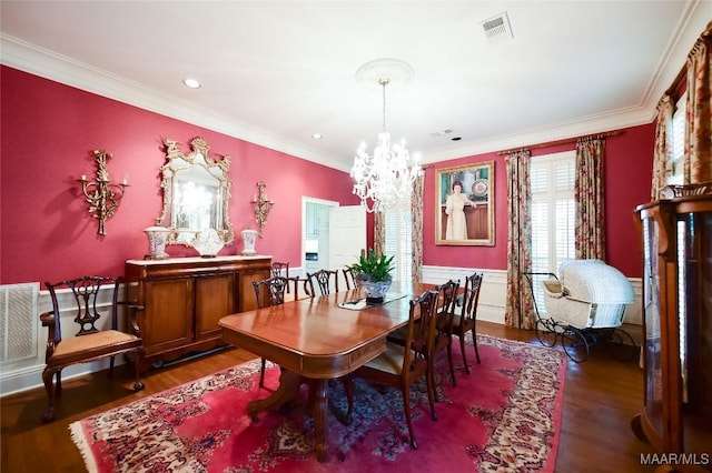 dining area featuring visible vents, crown molding, wood finished floors, and an inviting chandelier