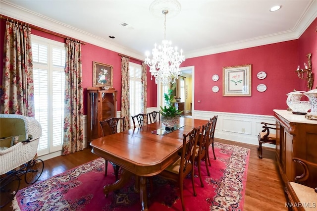 dining room featuring visible vents, wainscoting, wood finished floors, a notable chandelier, and ornamental molding