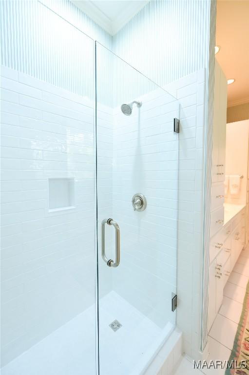 full bathroom featuring crown molding and a shower stall