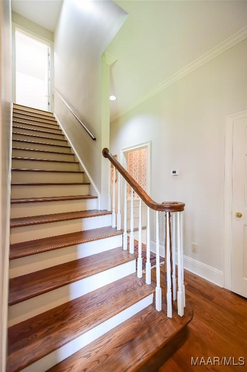 staircase featuring crown molding, recessed lighting, baseboards, and wood finished floors