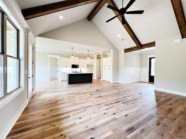 171 Mountain Laurel Rdg, Wetumpka, AL 36093 - unfurnished living room featuring beam ceiling, high vaulted ceiling, light wood-style floors, ceiling fan, and a decorative wall