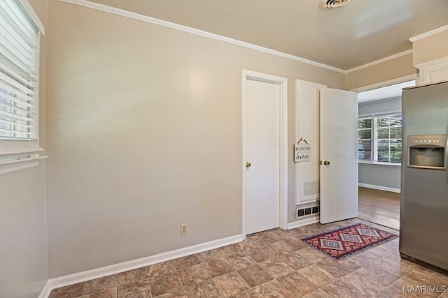 interior space featuring stainless steel fridge, baseboards, crown molding, and visible vents