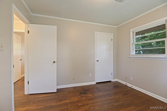 unfurnished bedroom with baseboards, ornamental molding, wood finished floors, and visible vents