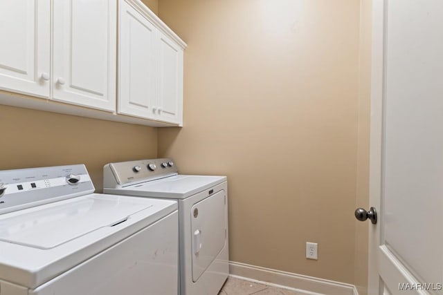 laundry area featuring separate washer and dryer, cabinet space, light tile patterned floors, and baseboards