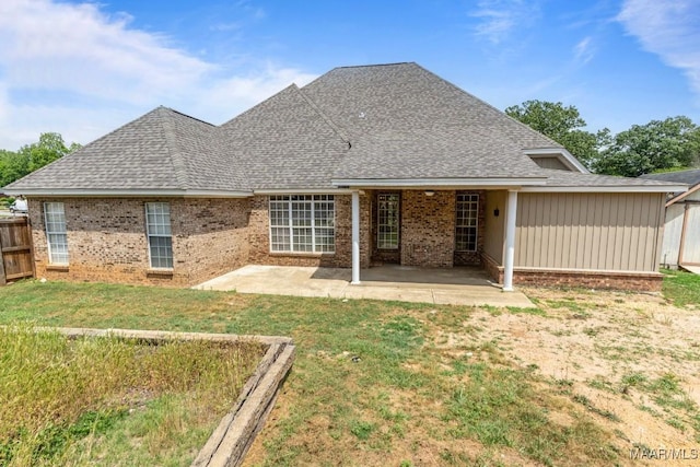 rear view of house featuring a lawn, brick siding, fence, and a patio