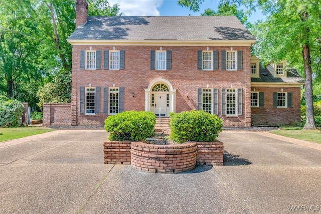 view of front of property with brick siding, a shingled roof, and a chimney