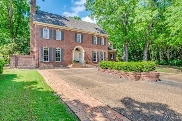 view of front facade with brick siding, roof with shingles, and a front lawn