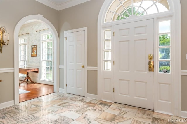 entryway with arched walkways, ornamental molding, baseboards, and marble finish floor