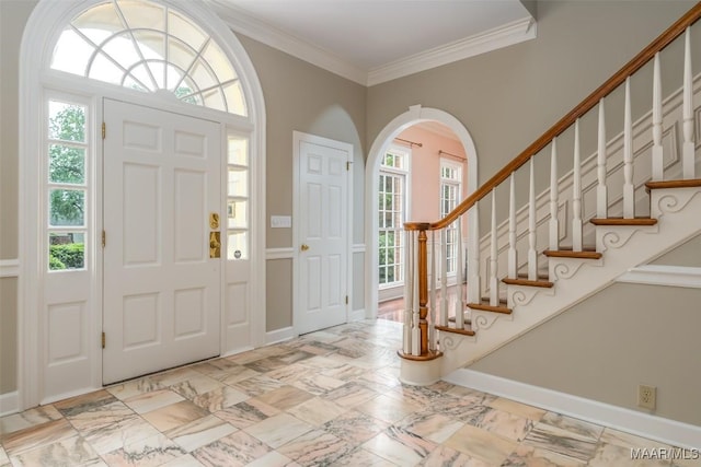 entryway with arched walkways, plenty of natural light, baseboards, and ornamental molding