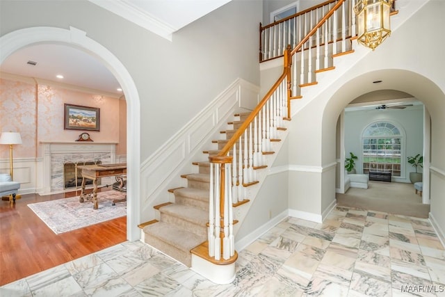 stairway featuring crown molding, arched walkways, ceiling fan, and a high ceiling