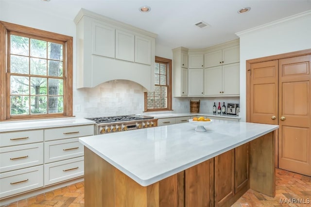 kitchen featuring visible vents, light countertops, plenty of natural light, and brick floor