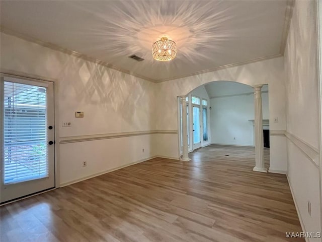 interior space with arched walkways, wood finished floors, baseboards, an inviting chandelier, and ornamental molding