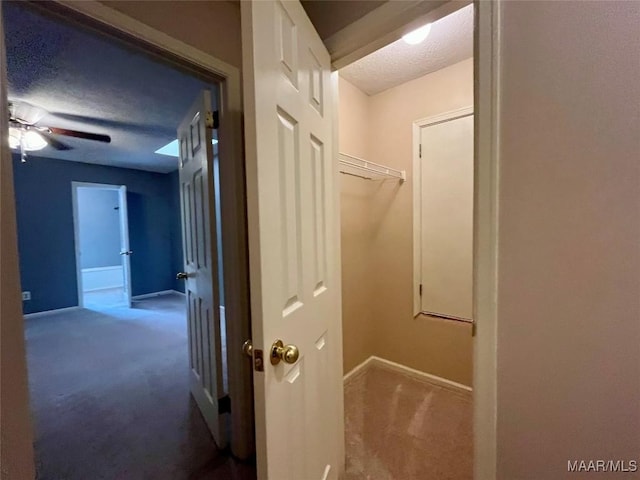 corridor featuring baseboards, a textured ceiling, and carpet