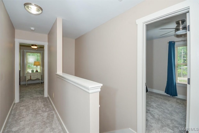 hall featuring baseboards, plenty of natural light, an upstairs landing, and light colored carpet