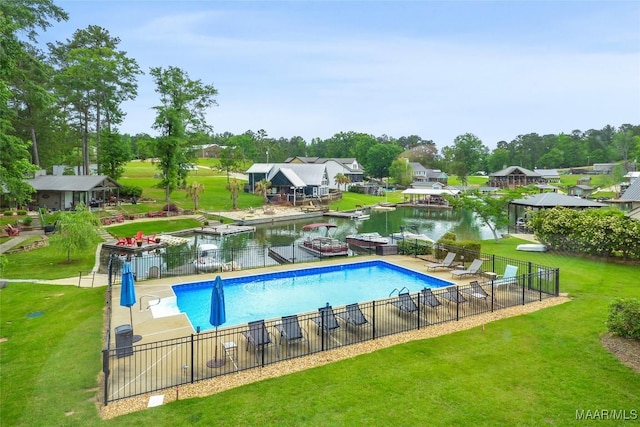 view of pool with fence, a fenced in pool, a water view, and a lawn