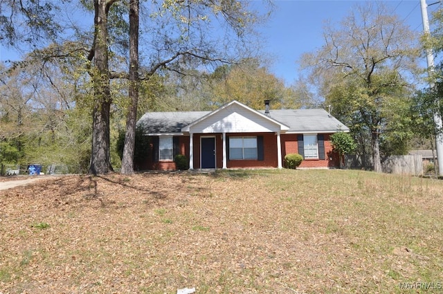 ranch-style home featuring brick siding, a front lawn, and fence