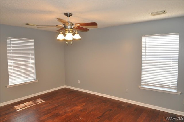 unfurnished room with a ceiling fan, baseboards, visible vents, and dark wood-type flooring