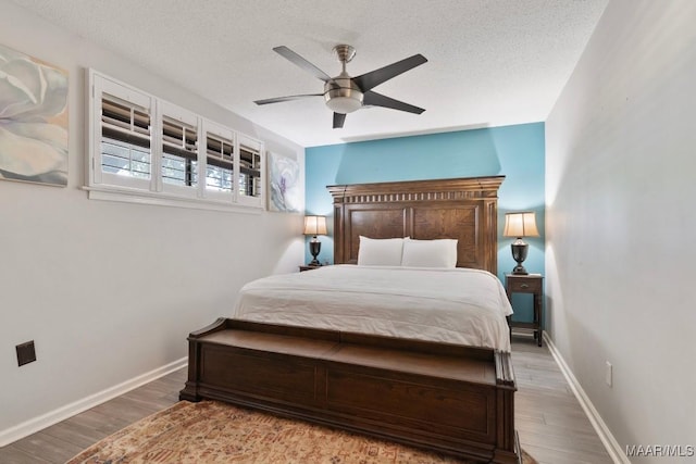 bedroom with baseboards, a ceiling fan, a textured ceiling, and wood finished floors