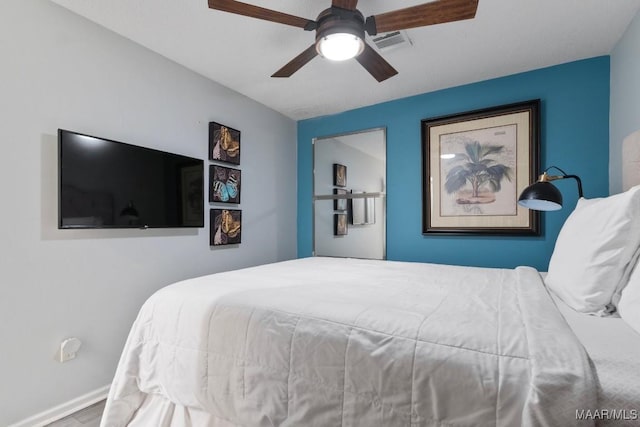 bedroom with baseboards, a ceiling fan, wood finished floors, and visible vents