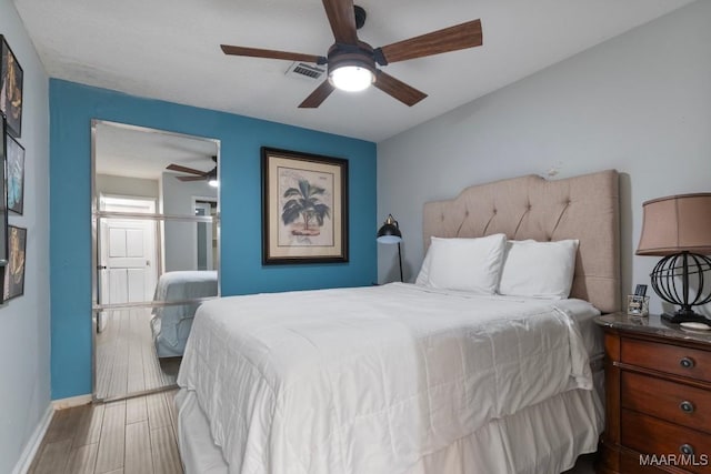bedroom featuring visible vents, baseboards, ceiling fan, and wood finished floors