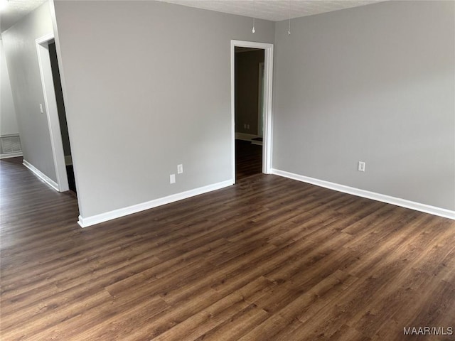 unfurnished room with baseboards and dark wood-style floors