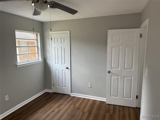 unfurnished bedroom with dark wood-style flooring, baseboards, a closet, and a textured ceiling