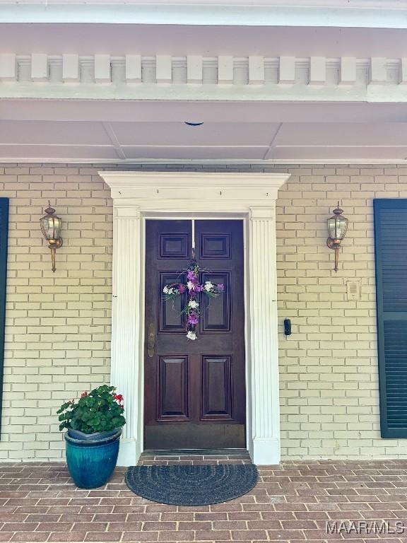 property entrance with covered porch and brick siding