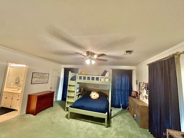 carpeted bedroom with visible vents, ornamental molding, connected bathroom, a textured ceiling, and a ceiling fan